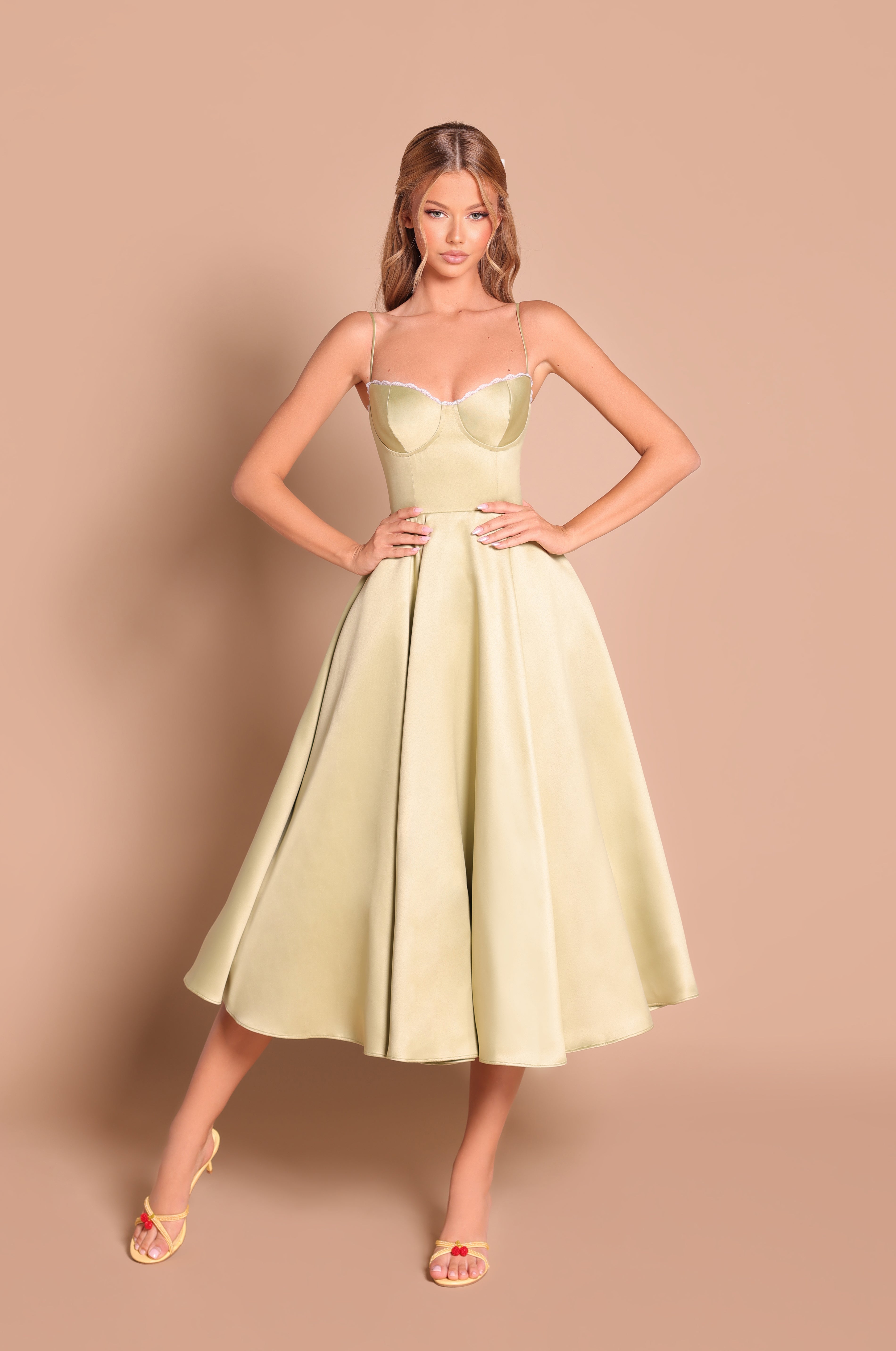 Woman in the Olive Green Satin Midi Wedding Guest Dress: Olivetta, featuring spaghetti straps and a flattering silhouette—perfect for making a chic statement as a wedding guest.